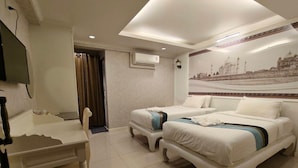 A hotel room with two beds, a desk, a chair, an air conditioning unit, and a wall-mounted television. - The Boone Hotel (Chiang Mai)