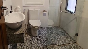 A bathroom with a large sink, toilet, and shower area. - The Boone Hotel (Chiang Mai)
