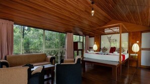 Una habitación amplia con una cama grande, dos sofás, techo de madera y una ventana con cortinas.