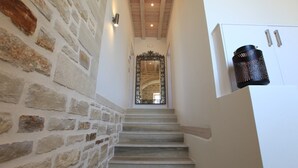Un escalier avec des murs en pierre et un miroir à cadre métallique au sommet.