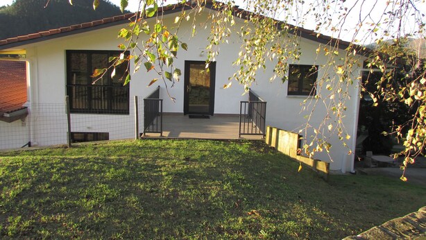 A single-story house with a front porch, a small garden, and a visible staircase leading to the entrance.