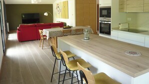 A modern kitchen with a wooden countertop, bar stools, and a dining table. - Sagarmintxe. Tourist apartment. (Berriatua)