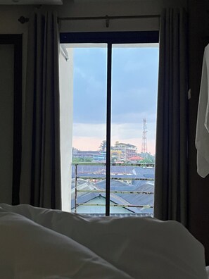 A hotel room with a large window, curtains, and a view of solar panels and buildings.