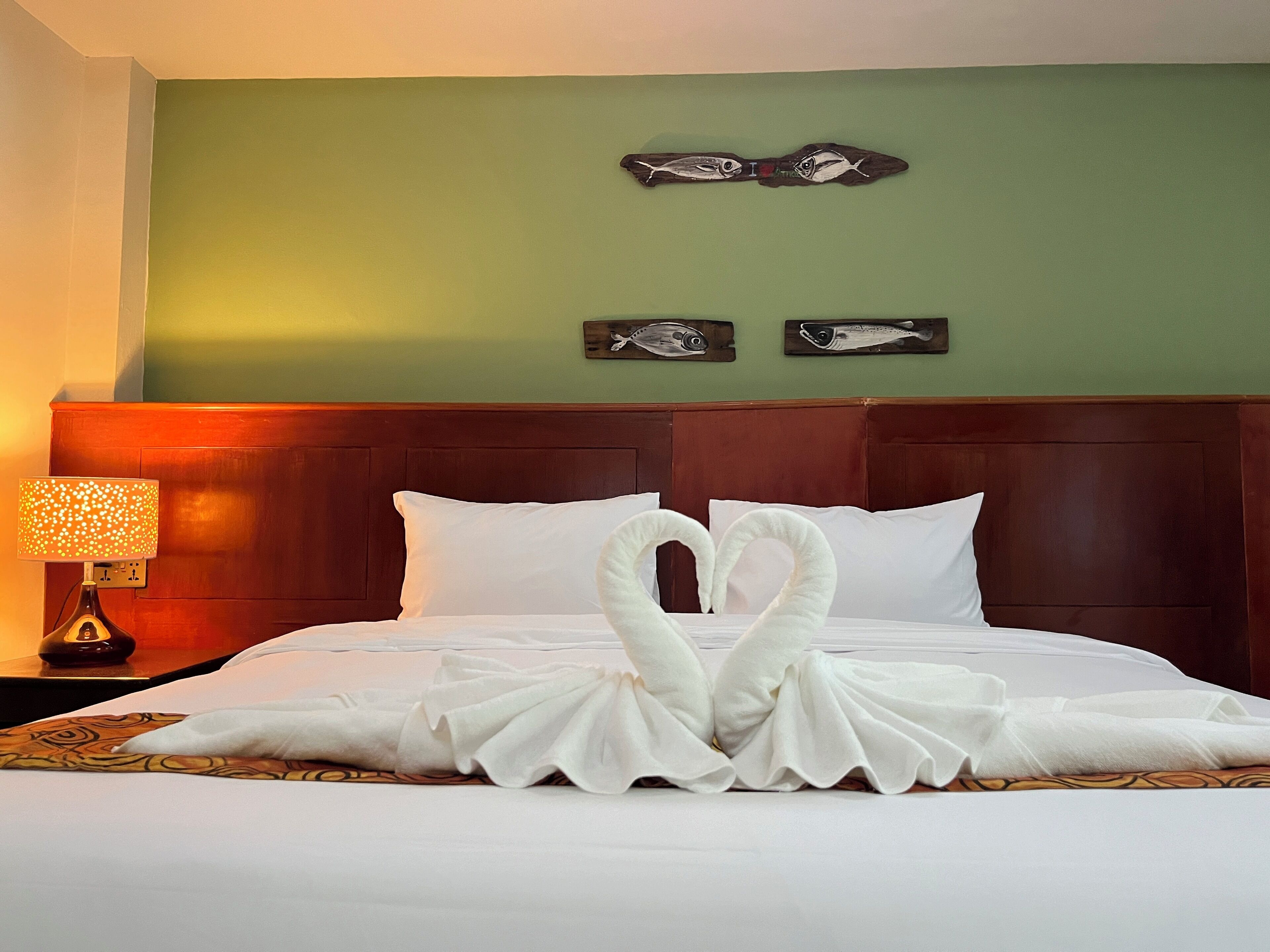 Hotelkamer met een bed, nachtkastje met lamp en wanddecoratie met vissen.