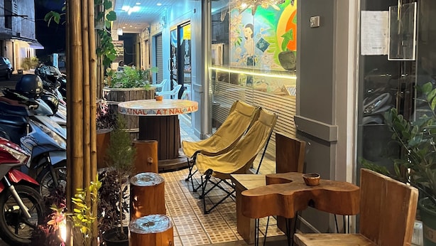 Un espace extérieur aménagé avec du mobilier en bois, une structure en bambou et une enseigne indiquant « Laverie ».