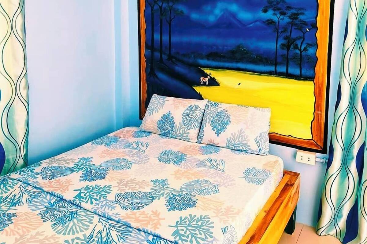 Un dormitorio con una cama, un cuadro de noche estrellada en la pared y cortinas.