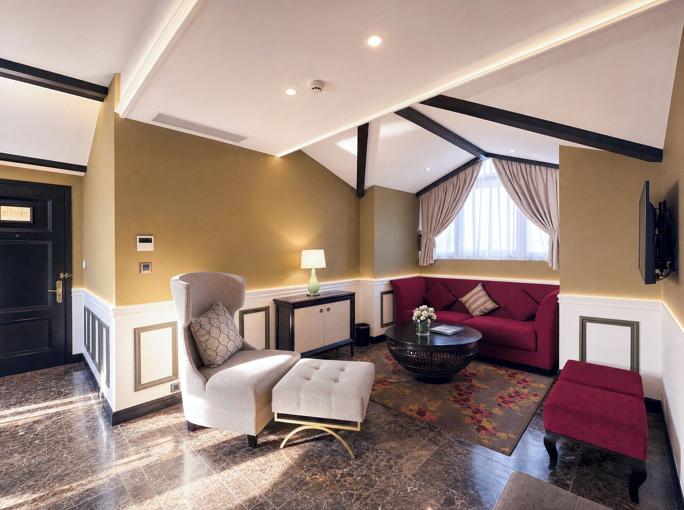 Una sala moderna con un sofá, un sillón, un reposapiés y una pequeña mesa con un jarrón.