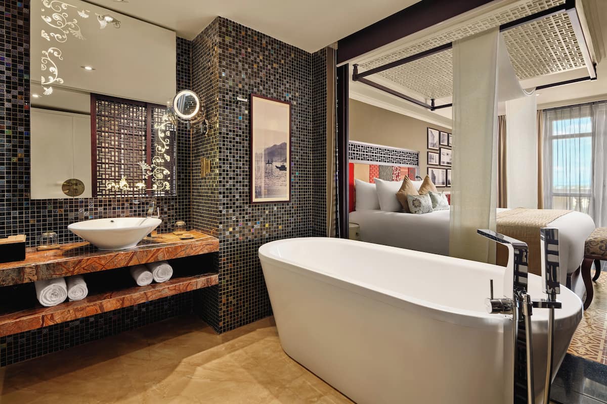 Un baño moderno con una bañera independiente, un espejo grande y un salpicadero de mosaico.