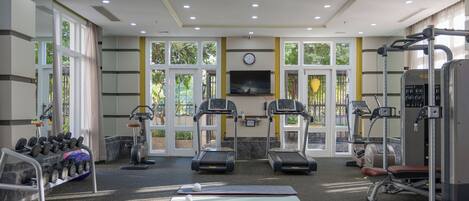 A gym with treadmills, weight machines, and dumbbells.