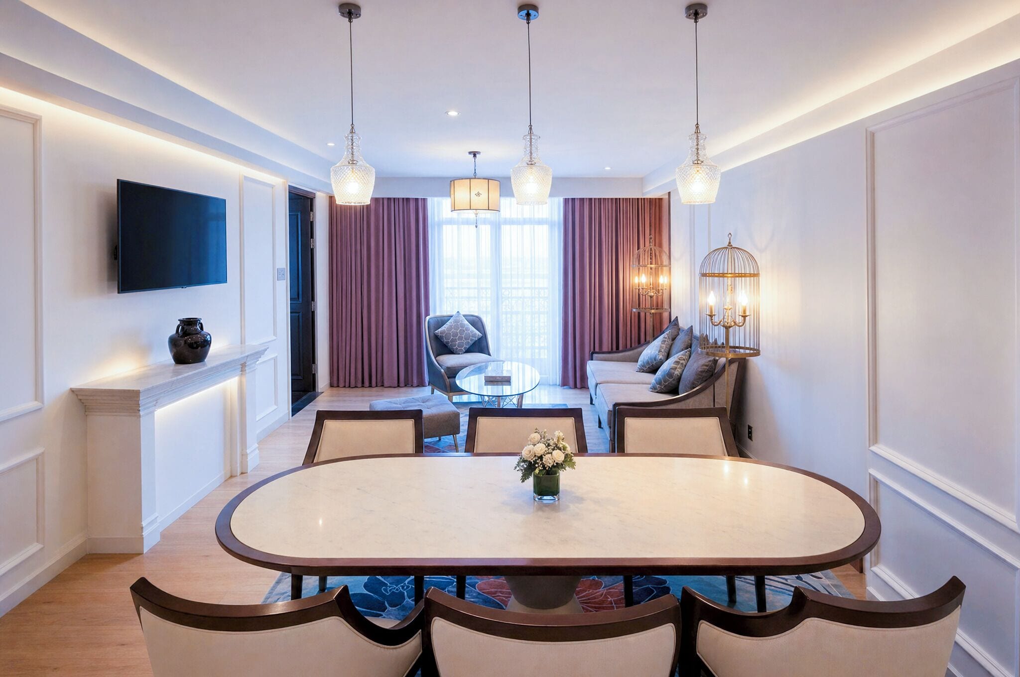 Een moderne hotelkamer met een zithoek, een zette, een aan de muur bevestigde televisie en een kroonluchter.