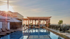 Un área de piscina en la azotea con sillones de descanso y una pérgola.