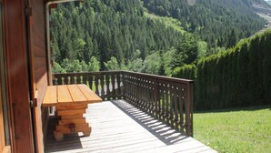 A wooden deck with a picnic table and a railing overlooking a forested mountain. - Chalet Jet d'Eau JD20 NATURE & MOUNTAIN  8 Pers. (Châtel)