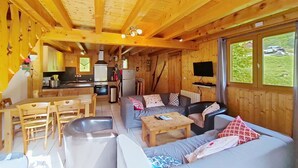 A cozy cabin interior with a dining area, sofa, and kitchen. - Chalet Papillon PPL NATURE & COSY 6 Pers. (Châtel)