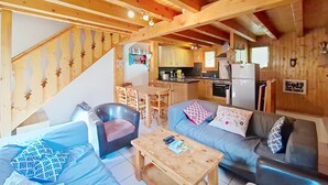 A cozy cabin interior with a wooden staircase, a dining area, and a kitchen. - Chalet Papillon PPL NATURE & COSY 6 Pers. (Châtel)