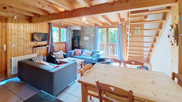 A wooden interior with a sofa, a dining table, and a stone fireplace. - Chalet Papillon PPL NATURE & COSY 6 Pers. (Châtel)