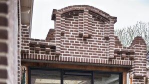 Een moderne badkamer met een groot bad, een glazen deur en een bakstenen buitenmuur.