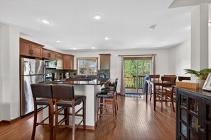 A modern kitchen with wooden cabinets, stainless steel appliances, and a bar area with stools. - 3 BDR Townhouse / Pet friendly / Great Location (Invermere)