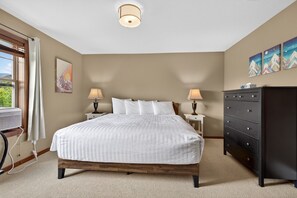 Une chambre à coucher avec un grand lit, des lampes de chevet, une commode et des œuvres d’art accrochées au mur.
