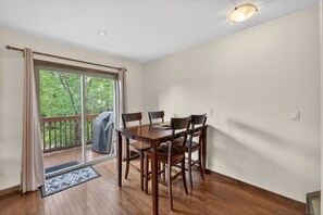 A dining area with a wooden table and chairs, a sliding glass door leading to a balcony, and a ceiling light fixture. - 3 BDR Townhouse / Pet friendly / Great Location (Invermere)