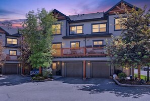A multi-story residential building with a balcony, garage doors, and a driveway. - 3 BDR Townhouse / Pet friendly / Great Location (Invermere)