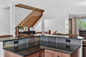 A modern kitchen with a granite countertop, wooden cabinets, and a wooden staircase. - 3 BDR Townhouse / Pet friendly / Great Location (Invermere)