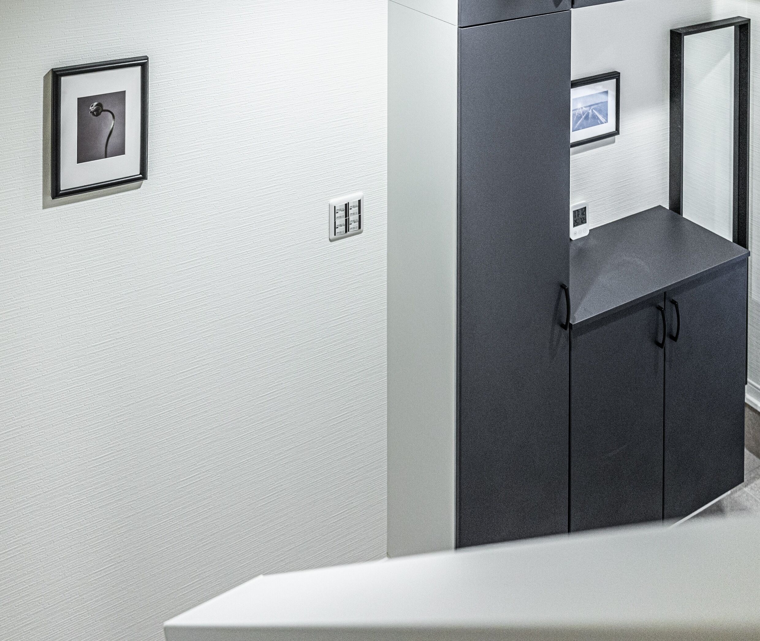 Une salle de bain moderne avec un lavabo blanc, un meuble sombre et un tableau encadré au mur.