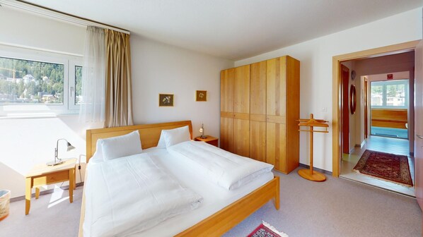A hotel room with a large bed, wooden wardrobe, bedside tables, and a view of the outdoors. - Well-kept holiday apartament house in a prime location in St. (St. Moritz)