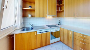 A compact kitchen with wooden cabinets, a sink, a dishwasher, and a stove. - Well-kept holiday apartament house in a prime location in St. (St. Moritz)
