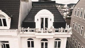 Um hotel de estilo arquitetônico clássico, com uma entrada imponente, varanda e uma placa com a inscrição 'HOTEL DOROTA'.