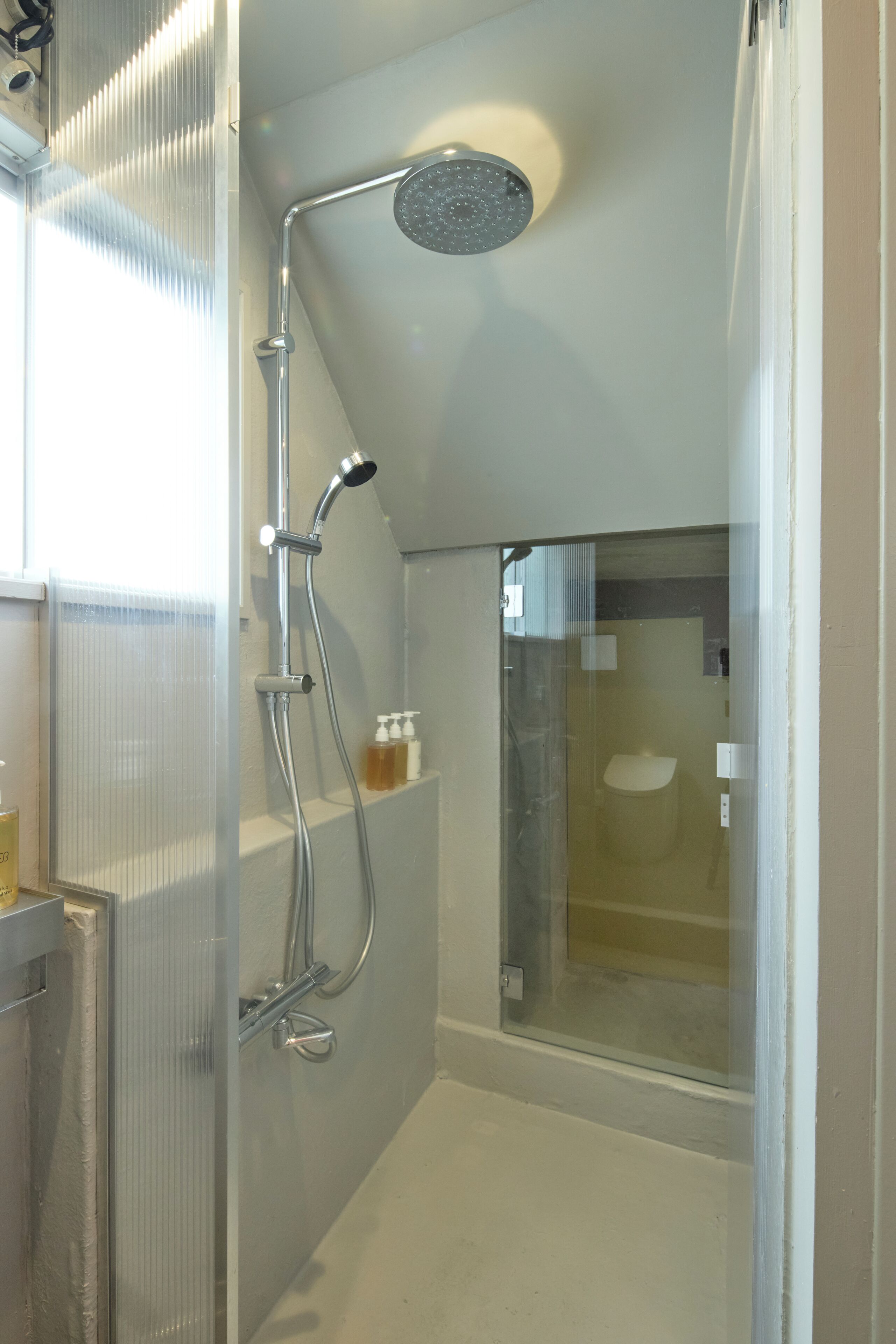 A modern shower with a glass enclosure, a handheld showerhead, and a wall-mounted faucet.