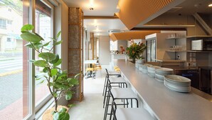 Una cocina moderna con una encimera amplia, taburetes de bar y vistas a la calle a través de grandes ventanales.