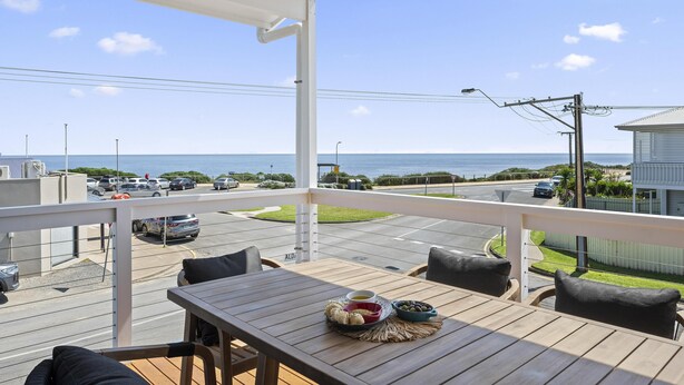 A wooden deck with a table and chairs, overlooking a street and ocean view. - C-Views ~ Aldinga Beach - Welcome To Your Dream Holiday House In Aldinga Beach (Aldinga Beach)
