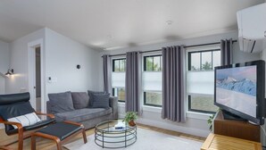 A modern living room with a sofa, armchair, coffee table, and a flat-screen TV. - Downtown Denver Guesthouse  Near RiNo (Denver)
