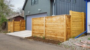 A residential property with a grey house, a wooden fence, and a driveway. - Downtown Denver Guesthouse  Near RiNo (Denver)