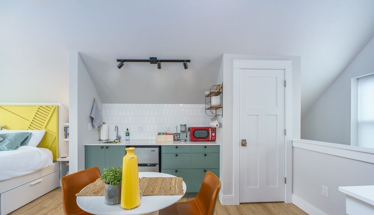 Un appartement compact comprenant un coin cuisine, un espace repas et une chambre.