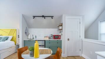 Un appartement compact comprenant un coin cuisine, un espace repas et une chambre.