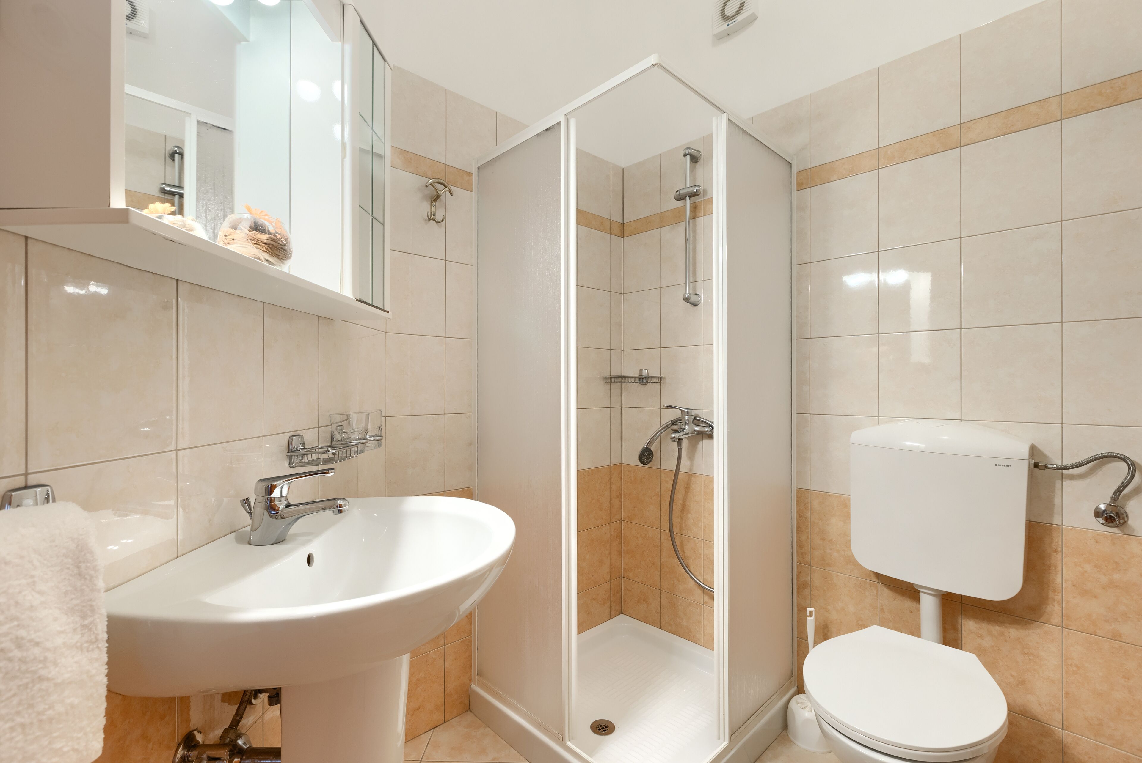 Et badeværelse med en hvid vask, toilet og brusekabine med glasvægge.