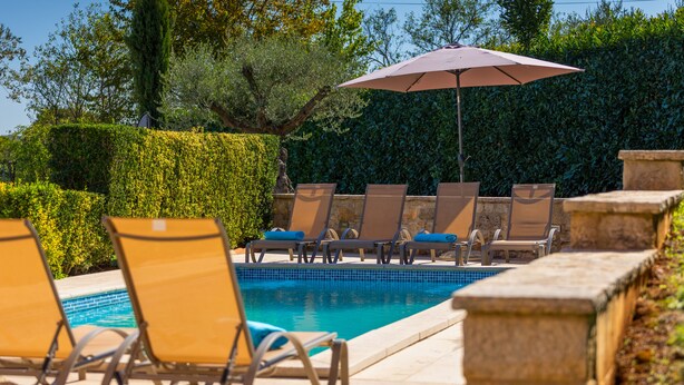 A poolside area with lounge chairs and an umbrella. - Holiday house  with pool,  garden, trampoline and a volleyball court (Vižinada)