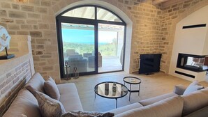 A living room with a stone wall, a large arched window, a sofa, a TV, and a fireplace.