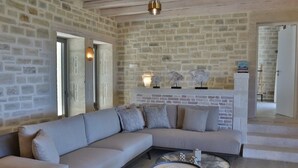 A modern living room with a stone wall, a grey sectional sofa, a round coffee table, and decorative wall sconces.