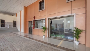 Una entrada moderna de edificio con suelo de baldosas, puerta de cristal y plantas en macetas.