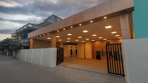 Un edificio moderno con entrada cubierta, varios pisos y un camino de acceso con portones.