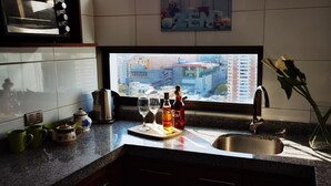 A kitchen with a large window, a sink, and various kitchen items on the counter. - Charming 1-bedroom apartment in Concepción with WiFi access (Concepción)