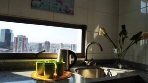 A kitchen with a city view, a sink, a kettle, and green cups on a mat. - Charming 1-bedroom apartment in Concepción with WiFi access (Concepción)