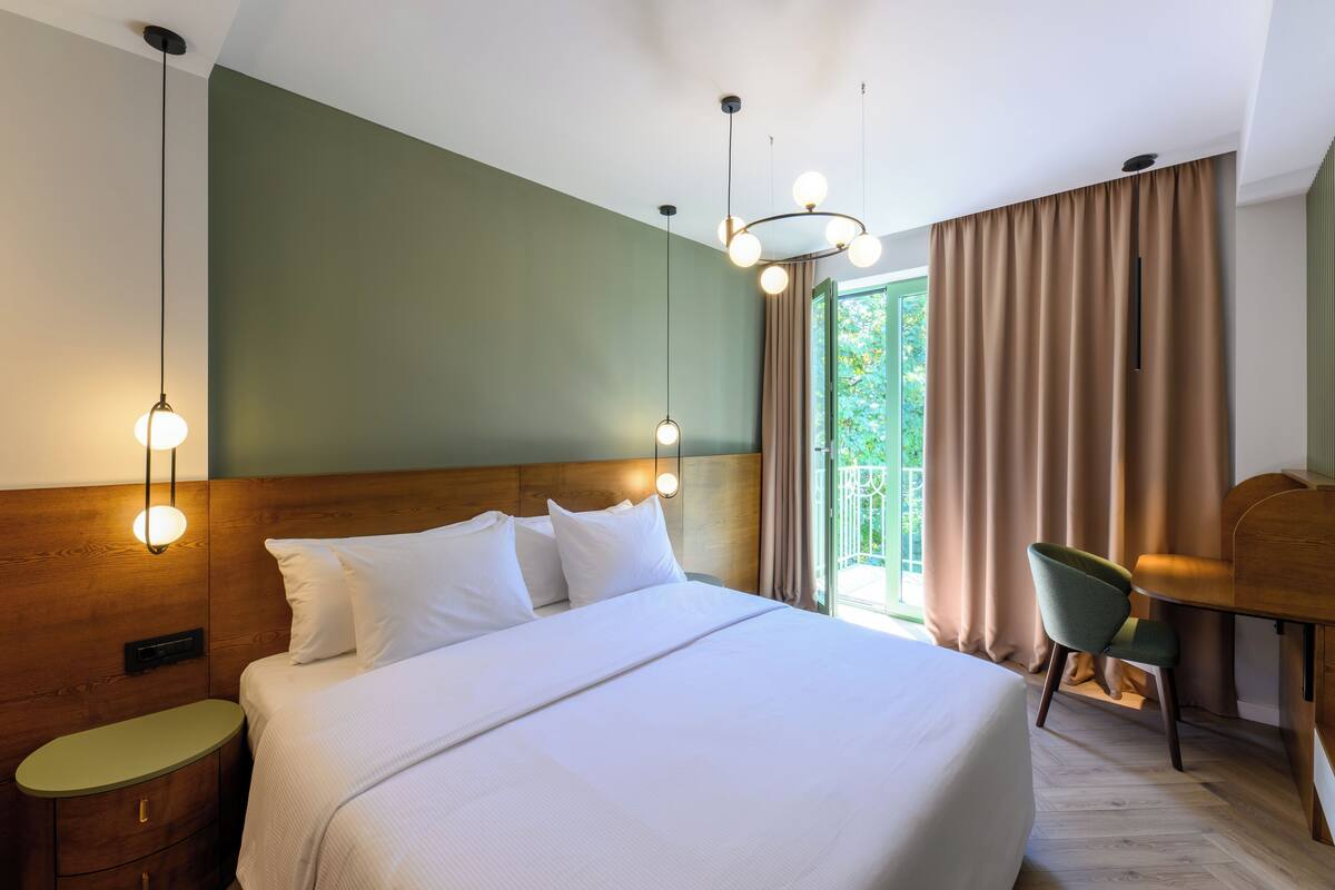 A hotel room with a large bed, bedside tables, a desk, and a chair.