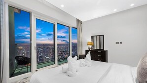A hotel room with a large bed, a desk, a chair, and a view of the city at dusk. - FIRST CLASS | 1BR | Amazing Marina Views (Marina)