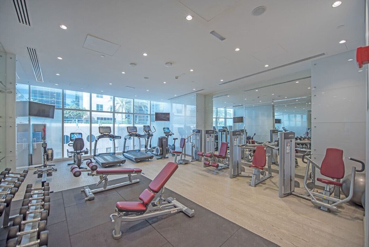 A modern gym with cardio machines, free weights, and exercise equipment.