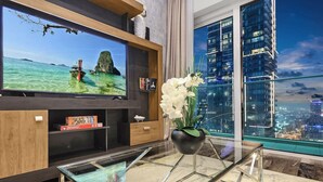 A modern living room with a large flat-screen TV, a glass coffee table, and a view of a cityscape at night. - FIRST CLASS | 1BR | Amazing Marina Views (Marina)