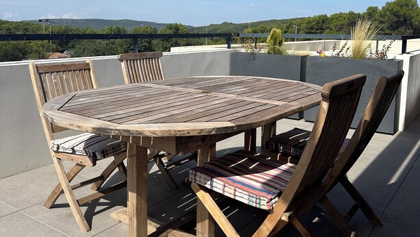 A round wooden table with chairs on a rooftop terrace, overlooking a scenic landscape. - Top floor luxury apartment in a secure residence  (Châteauneuf-le-Rouge)