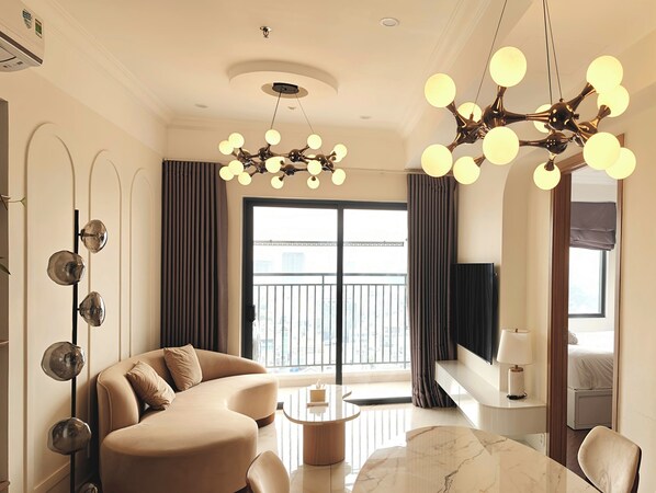 Ein modernes Wohnzimmer mit einer gebogenen Couch, einem Marmor-Couchtisch und einer Deckenleuchte mit mehreren kugelförmigen Lichtern.